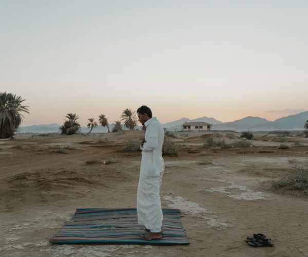 Person meditating peacefully outdoors during sunrise.